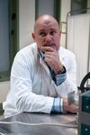 Bald doctor examines naked body of good-looking assistant in people's presence