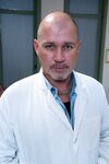 Bald doctor examines naked body of good-looking assistant in people's presence
