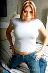 Busty amateur Tara strips to her white bra and panties to tease on the bed