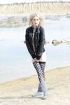 Charming blonde teen Nika removes leather coat and checked stockings on rocks