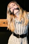 Cute blonde girl struggles against gag and ropes with her clothes still on