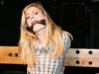 Cute blonde girl struggles against gag and ropes with her clothes still on