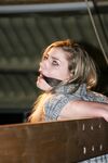 Cute blonde girl struggles against gag and ropes with her clothes still on