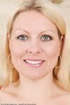 Middle-aged blonde woman Zoey Tyler poses in stockings by the fireplace