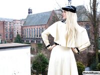 Classy blonde flashes the village below on her patio in latex attire