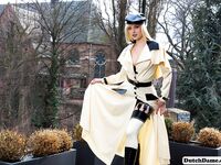 Classy blonde flashes the village below on her patio in latex attire