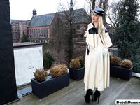 Classy blonde flashes the village below on her patio in latex attire