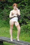 Natural redhead Lara showcases her pussy on a public bench in tan nylons