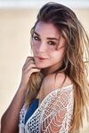 Erotic centerfold Lily C removes bikini to pose nude on driftwood at the beach