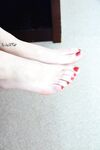 Blonde Axa Jay with oiled bare feet on her knees showing bald snatch