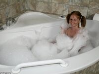 Young looking redhead Alyssa Hart jerks off her stepfather in the bathtub