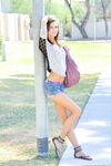 Slender girl in denim shorts stripping naked outdoors on public sidewalk