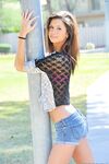 Slender girl in denim shorts stripping naked outdoors on public sidewalk
